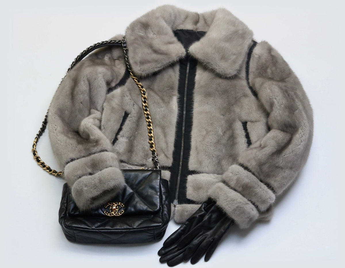 Veste en vison gris, sac Chanel 19 et gants en cuir noir posés à plat